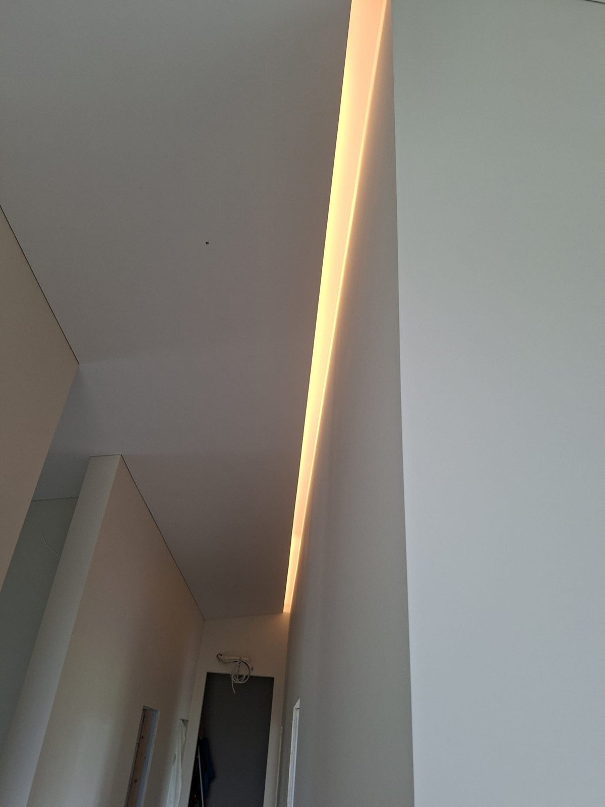 Paslėptas LED juostos apšvietimas sienos ir lubų kampe